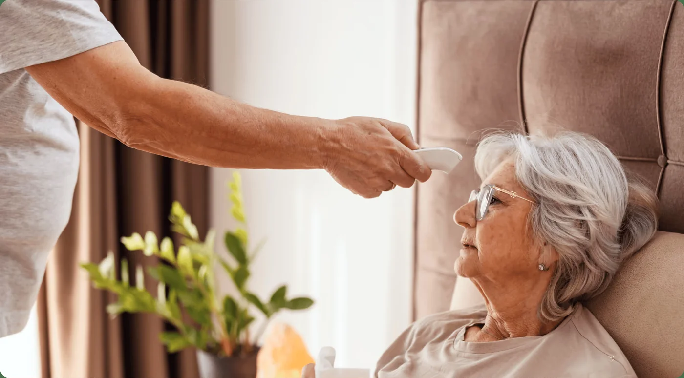 A caregiver offering a glass of water to an older woman