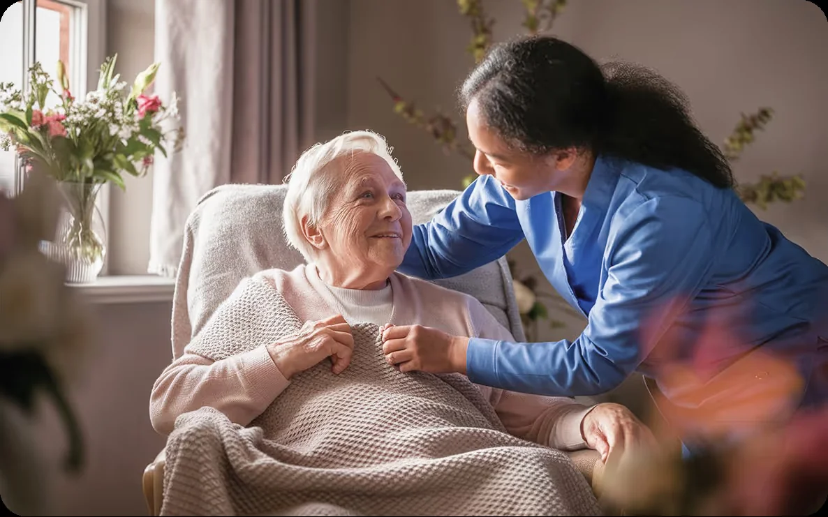 An older woman smiling with her caregiver in a sunlit living room
