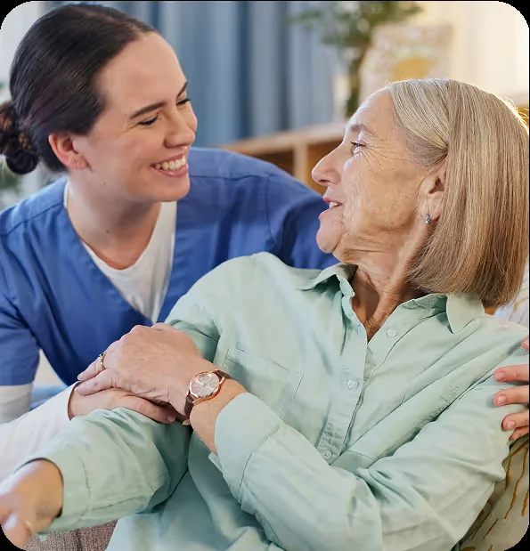 A caregiver and an older woman smiling together at home