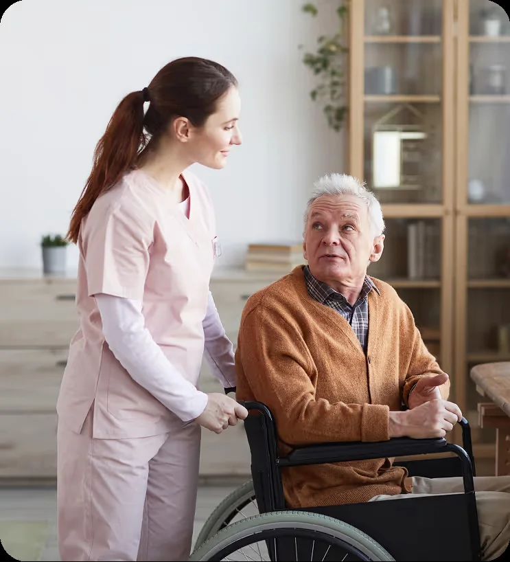 A care professional supporting an older man in a wheelchair