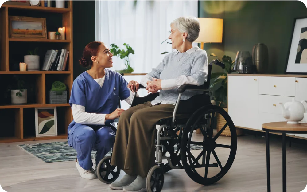 A caregiver in blue scrubs sharing a warm moment with a woman at home