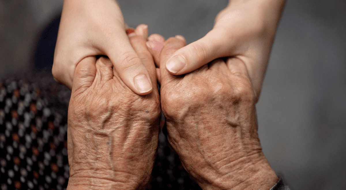 A reassuring hand held gently in a caregiver’s hands