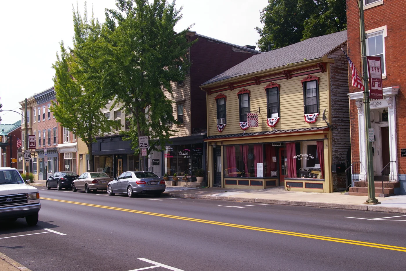 Tree-lined historic storefronts and a cafe along Main Street in Mechanicsburg, Pennsylvania.