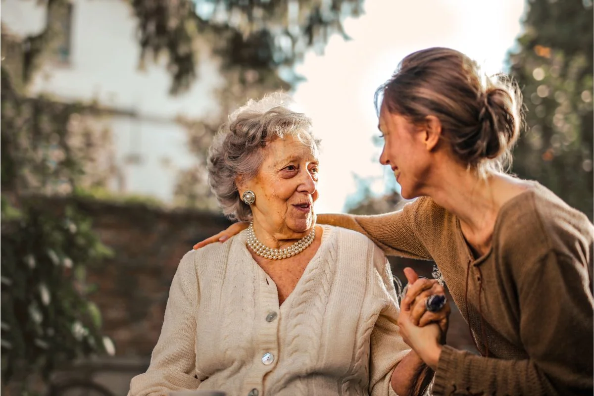 A woman and an older family member smiling together at home