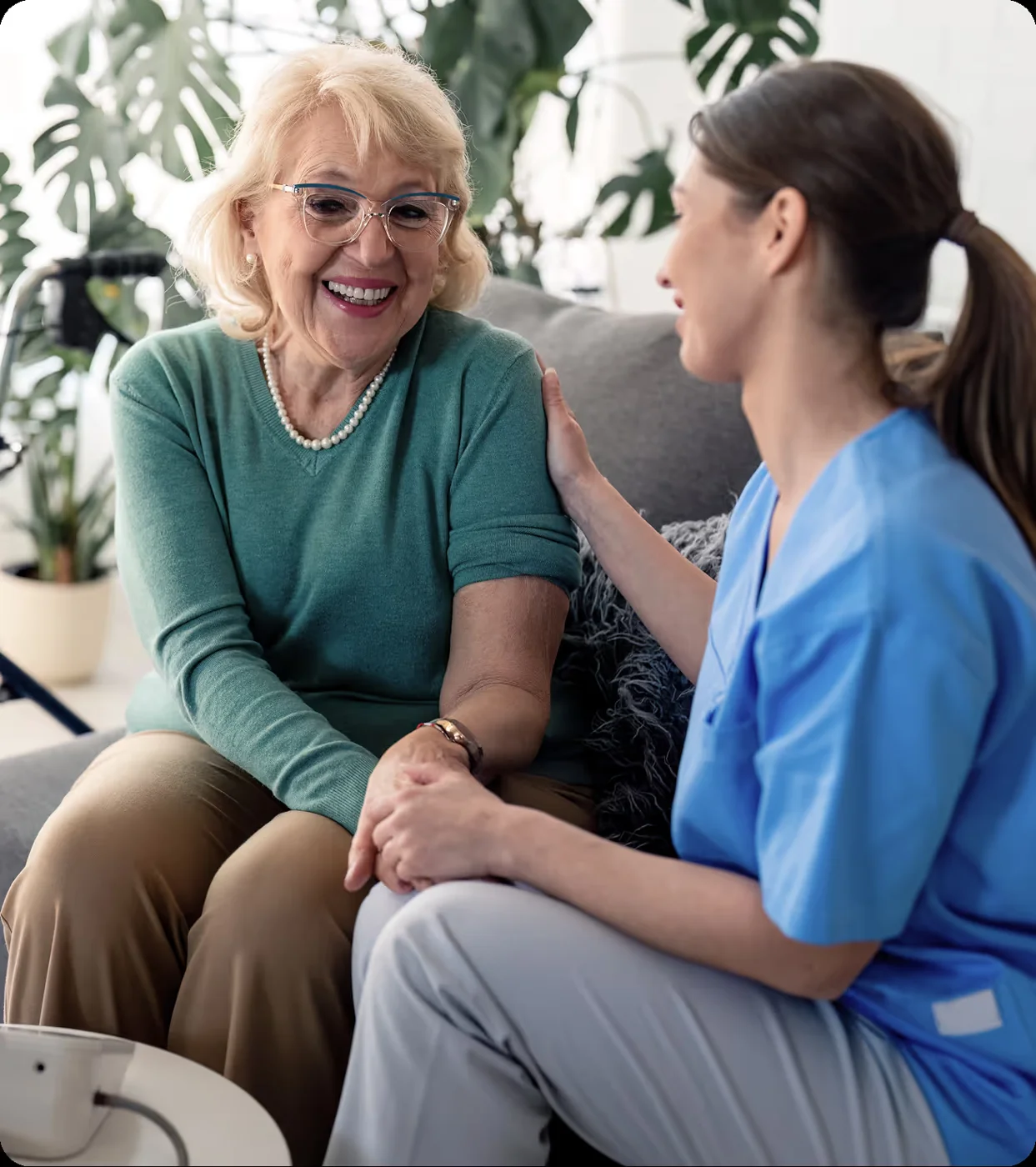 An older woman in a green sweater talking with her caregiver